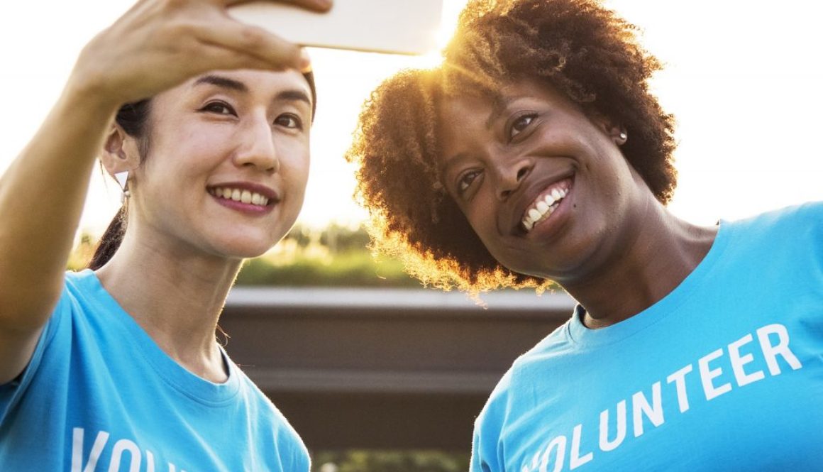 Two women with volunteer shirts on taking a selfie, published to: 
